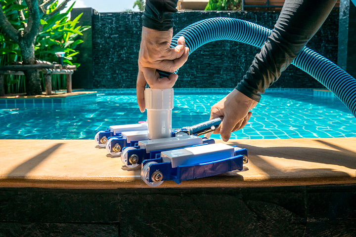 A person vacuums a pool, demonstrating effective cleaning techniques for maintaining pristine waters.