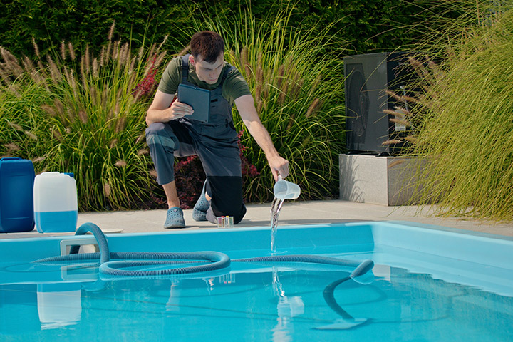A man uses a hose to clean a pool, highlighting essential maintenance for pristine swimming conditions.