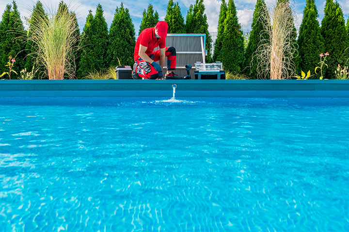 A man in a red shirt stands beside a sparkling pool, promoting professional pool cleaning services in Houston.