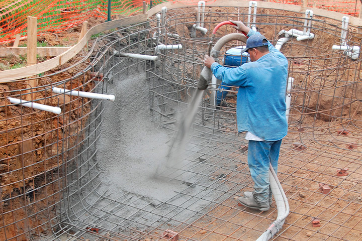 A man skillfully pouring concrete into a pool, highlighting a key step in pool construction in Houston.