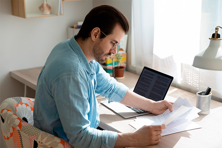 A man at a desk with a laptop and documents, illustrating the work of Right Pool Contractor in Austin.