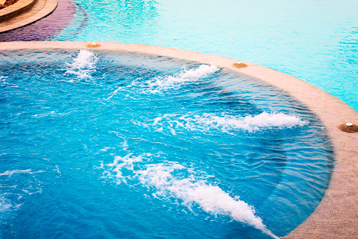 A pool equipped with water jets, highlighting swimming pool features for homes in Austin and Houston.